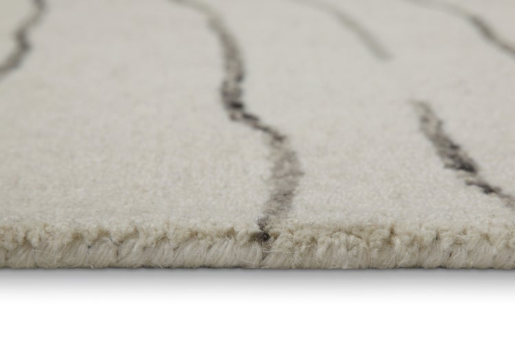 Nahaufnahme eines gewebten Teppichs mit Wellenmuster, zeigt die Florhöhe und Struktur an der Kante.