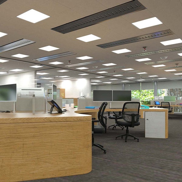 Helles Großraumbüro mit quadratischen LED-Deckenpanels, Schreibtischen in Holzoptik und ergonomischen Bürostühlen im modernen Stil.