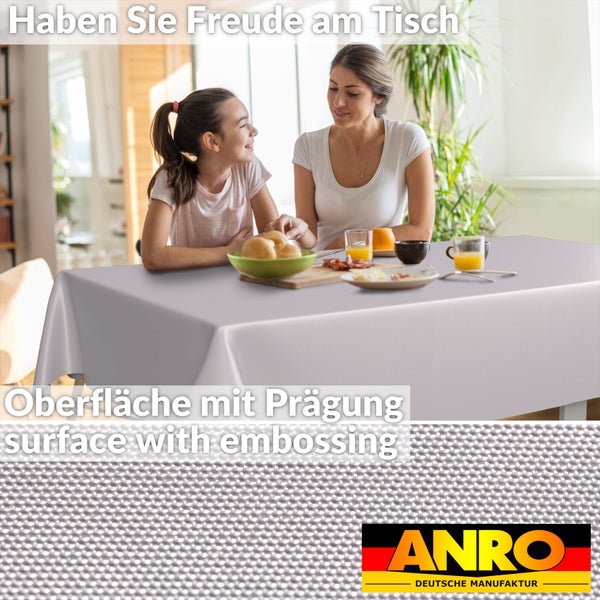 Rechteckige Tischdecke mit geprägter Oberfläche in einem hellen Raum mit Mutter und Tochter am gedeckten Tisch. ANRO Deutsche Manufaktur Logo.
