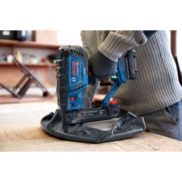 Person verwendet einen Akku-Nagler von Bosch zum Befestigen von Stoff an einem Möbelstück