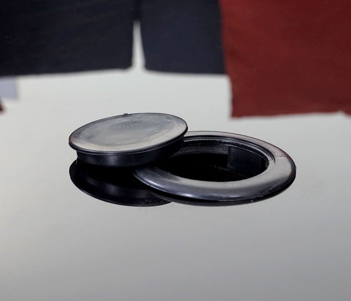 Runder schwarzer Kabeldurchlass aus Kunststoff mit abnehmbarem Deckel für Schreibtische.