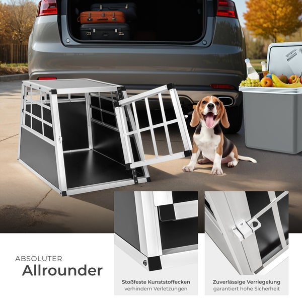 Aluminium Hundebox vor einem geöffneten Kofferraum mit Gepäck und einem Hund