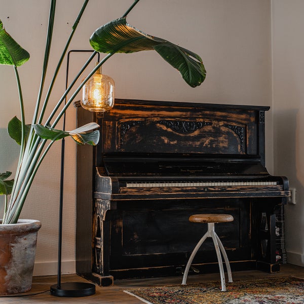 Dekoratives Zimmer mit Stehlampe, Pflanze, Klavier und Hocker