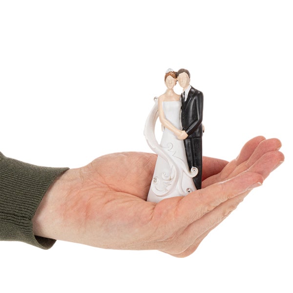 Miniatur-Hochzeitsfiguren Braut und Bräutigam auf einer Handfläche zur Veranschaulichung der Größe.