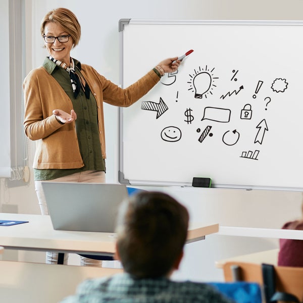 Eine Frau präsentiert an einem magnetischen Whiteboard mit Aluminiumrahmen in einem hellen Besprechungsraum mit Laptop.