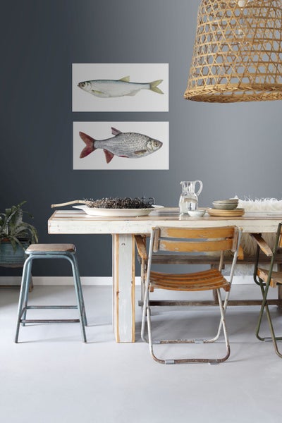 Esszimmer mit Holztisch, Stühlen, Deko und Fischbildern an der Wand