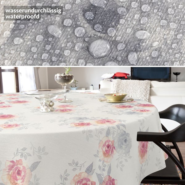 Runde Tischdecke mit floralem Rosenmuster in einem Wohnzimmer. Die Detailaufnahme zeigt die wasserundurchlässige Oberfläche mit Wassertropfen.