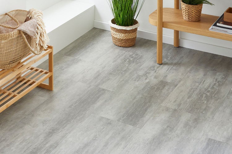Hellgrauer Vinylboden in Steinoptik in einem hellen, modern eingerichteten Raum mit Holzregal und Pflanze.
