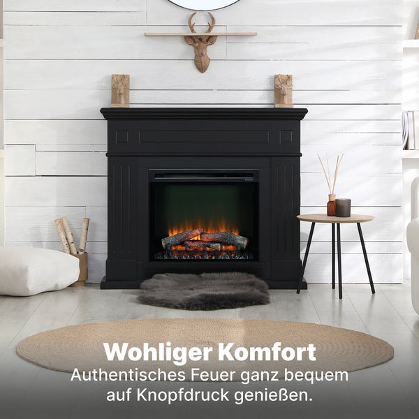 Schwarzer Elektrokamin mit brennenden Holzscheiten und Kaminsims vor weißer Holzvertäfelung mit Hirschkopfdeko, Beistelltisch und Teppichen.