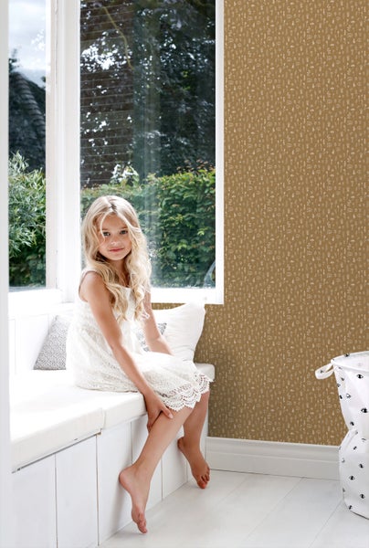 Mädchen sitzt vor einer Wand mit Blumentapete