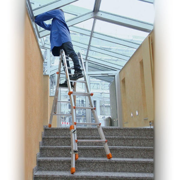 Eine Person steht auf einer Mehrzweckleiter auf einer Treppe und arbeitet an einem Glasdach.