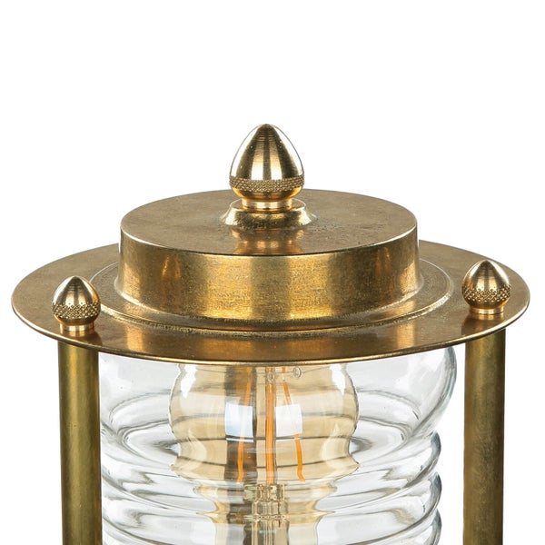 Detailaufnahme einer Tischleuchte mit einem klaren Glasgehäuse und goldenen Akzenten