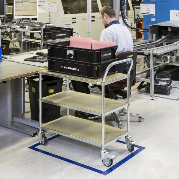 Servierwagen mit drei Ablagen und Rollen in einer Produktionshalle