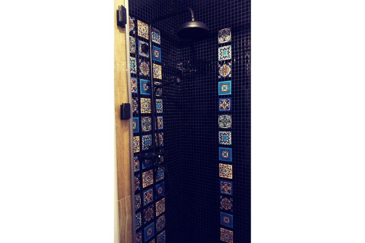 Dusche mit dunklen Mosaikfliesen und dekorativen Fliesen