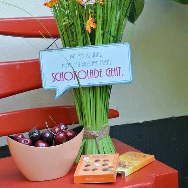 Dekorative Szene mit Schild, Kirschen und Schokolade auf einer Bank