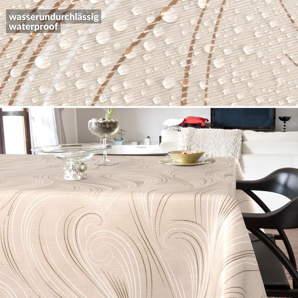 Wasserundurchlässige Tischdecke mit beigem Wellenmuster auf einem Esstisch im Wohnzimmer, Detailansicht mit Wassertropfen auf der Oberfläche.
