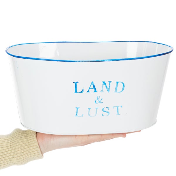 Ovaler Pflanztopf aus Metall in Weiß mit blauem Rand und der Aufschrift LAND und LUST.