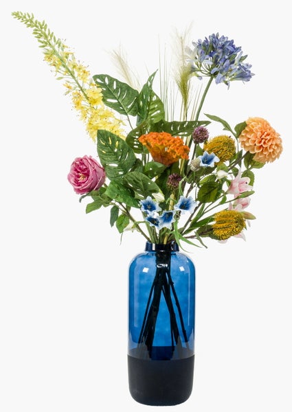 Künstlicher Blumenstrauß mit verschiedenen Blüten und Blättern in einer blauen Glasvase.