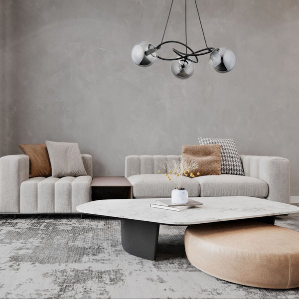 Moderne Pendelleuchte mit drei Glaskugeln in einem Wohnzimmer mit Sofa, Couchtisch und Teppich