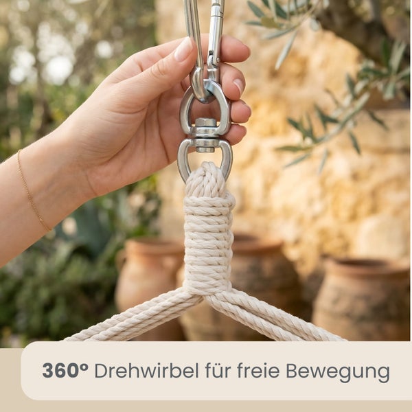 Hand hält einen metallenen 360 Grad Drehwirbel mit Karabinerhaken an einem geflochtenen Seil für freie Bewegung.