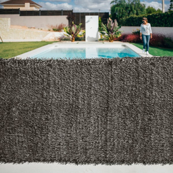 Sichtschutzmatte in Kunsthecken-Optik aus Kunststoff in Anthrazit vor einem modernen Garten mit Swimmingpool und Rasenfläche.
