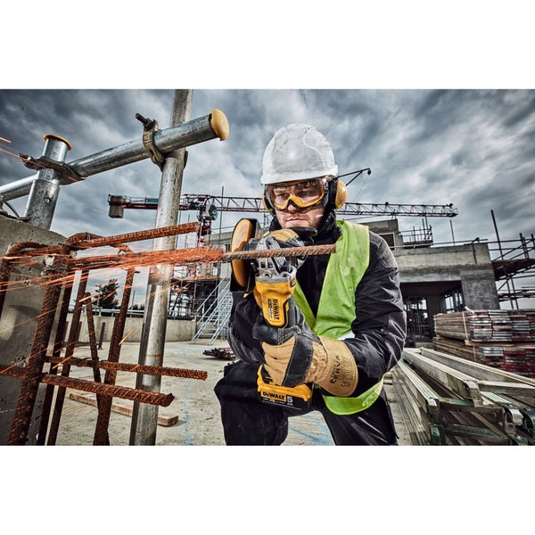 Bauarbeiter mit Sicherheitsausrüstung schneidet Bewehrungsstahl mit einem DeWalt Akku-Winkelschleifer auf einer Baustelle.
