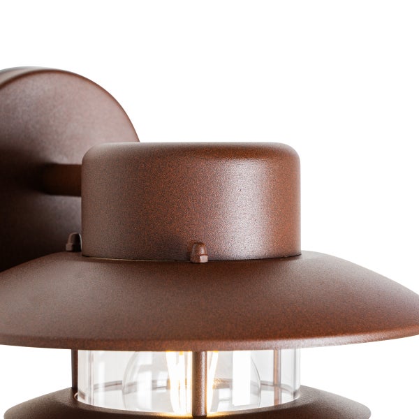 Detailansicht einer rostfarbenen Außenwandleuchte mit klarem Glas und sichtbarem LED-Filament-Leuchtmittel.