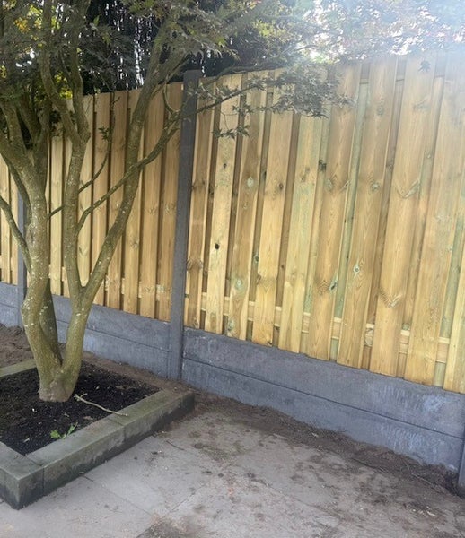 Holzzaun mit Betonpfosten und Bodenplatten im Garten