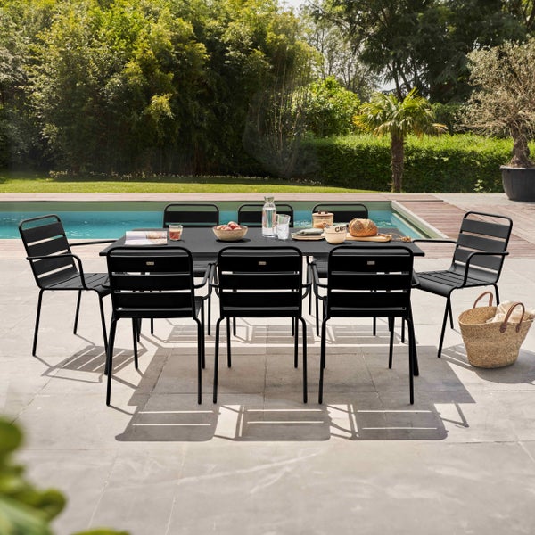 Moderne Garten-Essgruppe mit schwarzem Metalltisch und acht Stühlen auf einer Steinterrasse neben einem Pool.