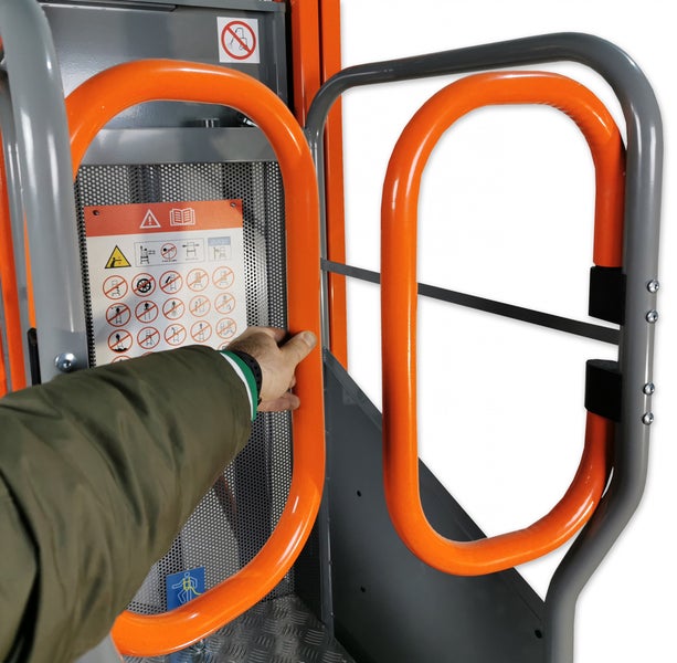 Hand am orangefarbenen Sicherheitsgeländer einer Hebebühne mit sichtbaren Sicherheitshinweisen.