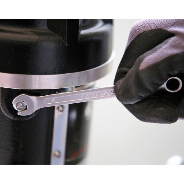 Ein Schraubenschlüssel der Marke Brillant wird benutzt, um eine Schraube an einem schwarzen Objekt zu befestigen.