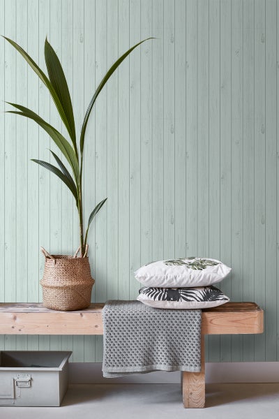 Dekoratives Interieur mit Holzbank, Kissen und Zimmerpflanze vor einer Holzwand.