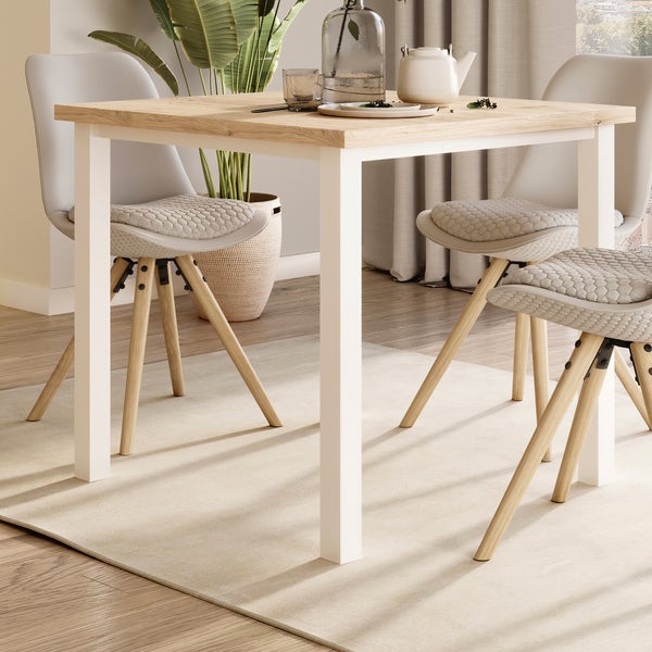 Esszimmertisch mit Holzplatte und weißen Tischbeinen kombiniert mit modernen Stühlen mit gepolsterter Sitzfläche in einem hellen Wohnraum.