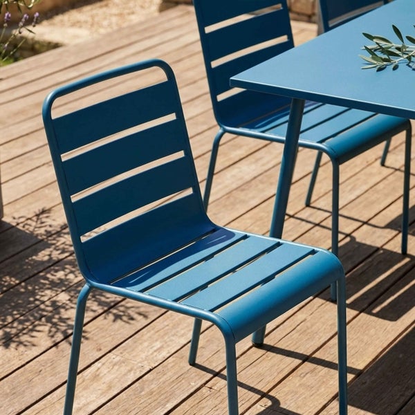Moderne blaue Gartenmöbel aus Metall auf einer hellen Holzterrasse, bestehend aus Stühlen mit Lattendesign und einem passenden Tisch.