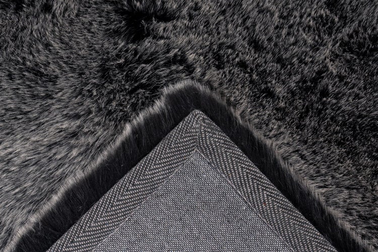 Nahaufnahme eines Kunstfellteppichs mit weichem Flor und gemusterter Textilrückseite.