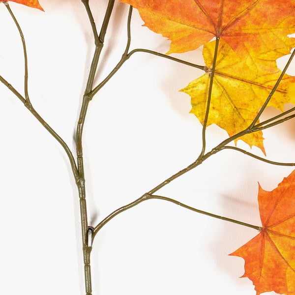 Nahaufnahme eines künstlichen Ahornzweigs mit herbstlichen Blättern.