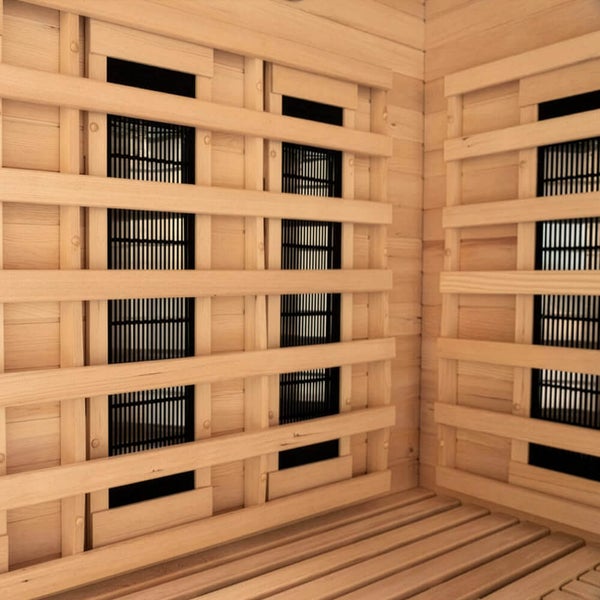 Infrarotstrahler in einer Sauna aus hellem Holz mit schützender Holzverkleidung und Lattenrost.