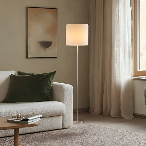 Wohnzimmer mit Stehlampe, Sofa, Kissen, Teppich und Kunstwerk für eine gemütliche Atmosphäre