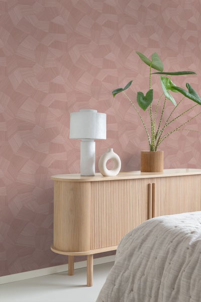 Geometrisch strukturierte Tapete in einem modernen Raum mit Sideboard aus hellem Holz, weißer Lampe und Zimmerpflanze.