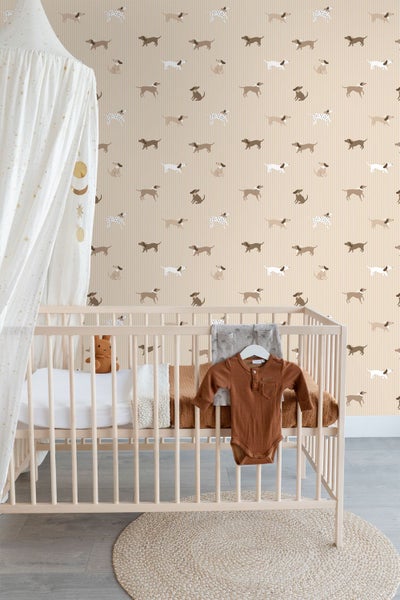 Helles Kinderzimmer mit einem Babybett aus Holz, Baldachin und Vliestapete mit Hundemotiv auf gestreiftem Untergrund.