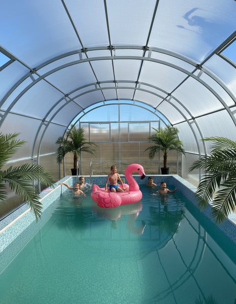 Schwimmbad mit Poolüberdachung und Kindern mit Flamingoluftmatratze