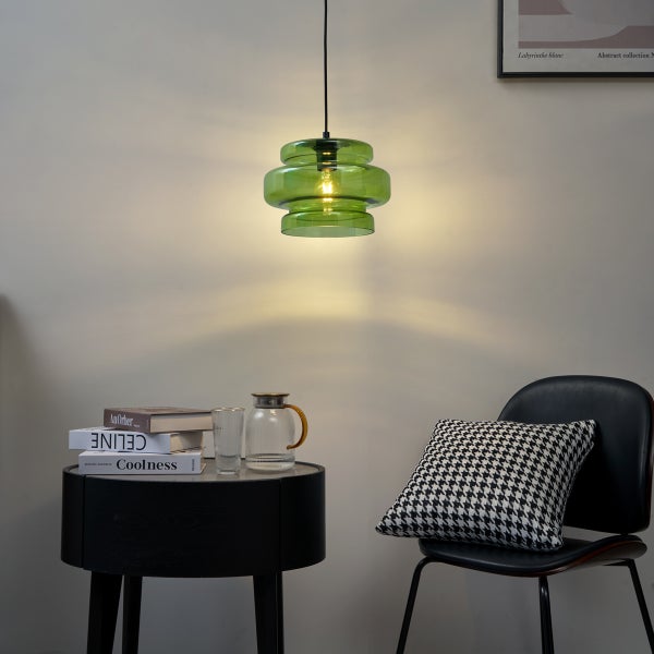 Szene mit einer grünen Hängelampe, einem schwarzen Beistelltisch und einem Stuhl.