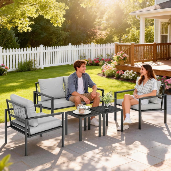 Modernes Garten-Lounge-Set aus Metall mit Sofa, Sesseln und Tischen auf einer hellen Terrasse im organisierten Garten mit zwei Personen.