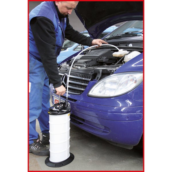 Eine Person benutzt eine Ölabsaugpumpe an einem Auto, um einen Ölwechsel durchzuführen.