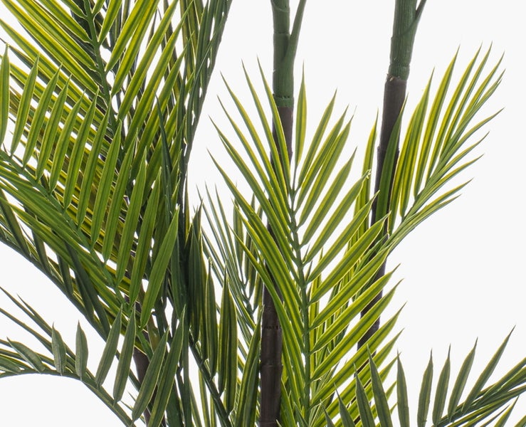 Nahaufnahme einer künstlichen Palme mit grünen Palmwedeln und dunklen Stämmen.