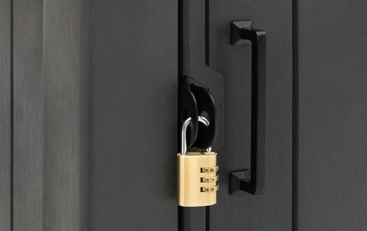 Messingfarbenes Zahlenschloss an einem schwarzen Türgriff und einer Verriegelung.