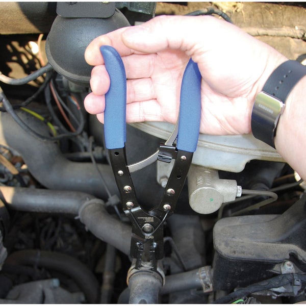 Eine Person verwendet eine Schlauchschellenzange im Motorraum eines Fahrzeugs.