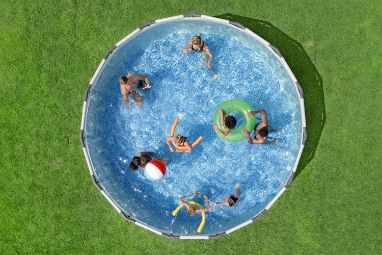 Draufsicht auf einen runden Aufstellpool mit Rahmen im Garten, in dem mehrere Personen mit Schwimmhilfen spielen.