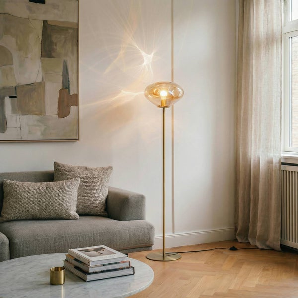 Stehlampe mit Glaskugel-Leuchtenschirm in einem Wohnzimmer mit Sofa, Couchtisch und Gemälde