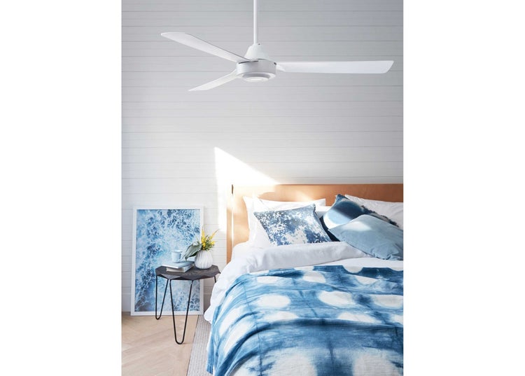 Deckenventilator in modernem Design montiert in einem hell eingerichteten Schlafzimmer mit blauen Textilien.